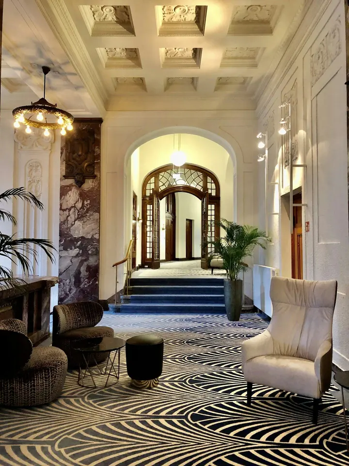 Vestíbulo de un hotel con butacas y una puerta en arco