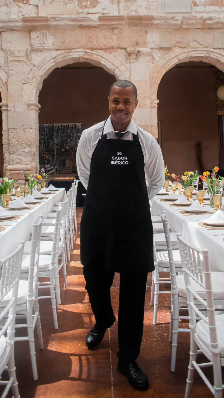 Camarero de Sabor Ibérico con el delantal de la marca en un salón preparado para un evento