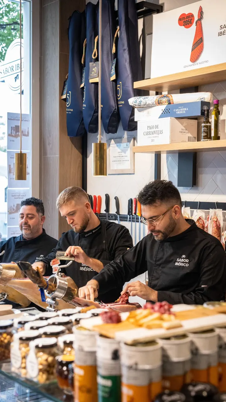 Equipo de Sabor Ibérico preparando producto en el mostrador de su tienda de Madrid